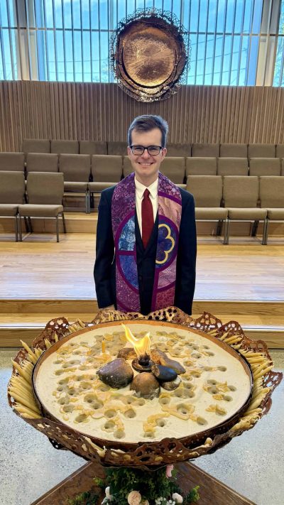 Rev Alex standing in the sanctuary between the chalice and the dossal
